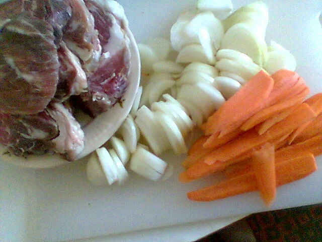 Pork steak on a bed of onions and carrots with boiled potatoes