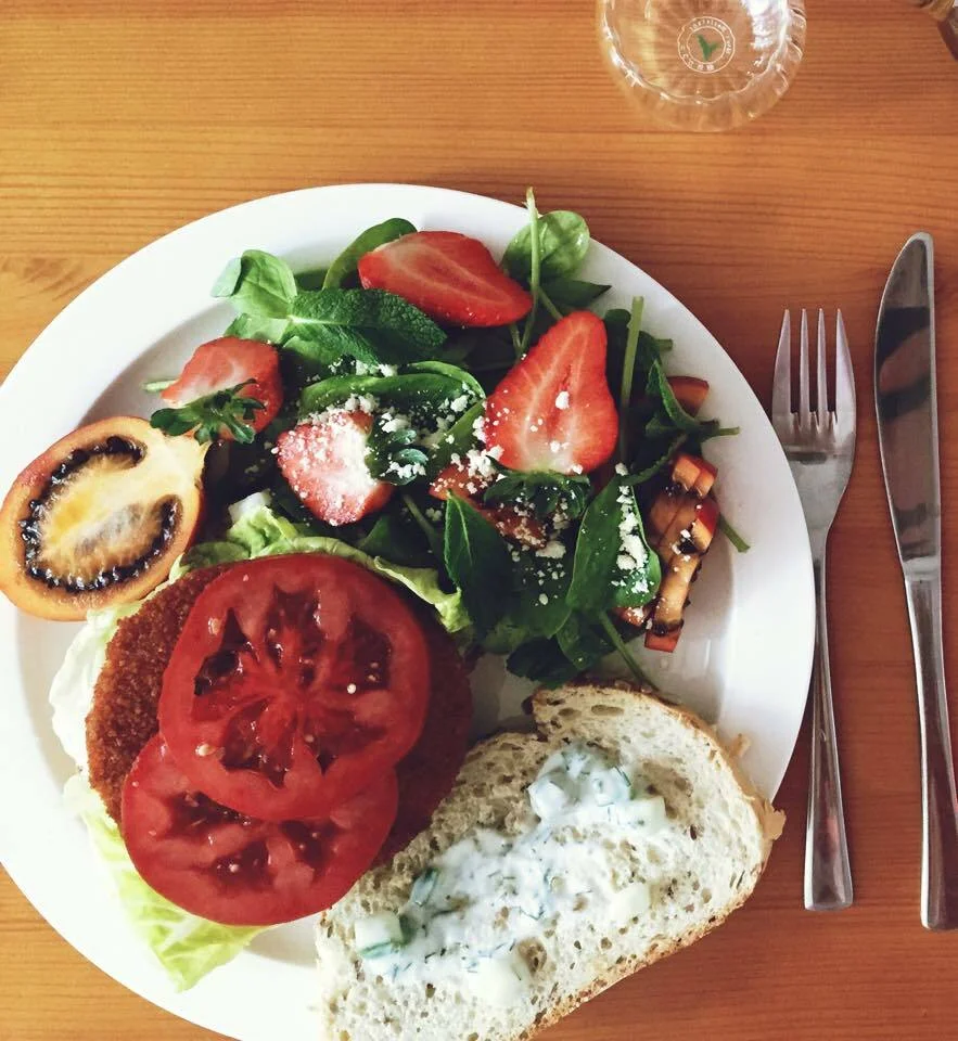 Vegetarian burger with Tzatziki sauce and spinach salad with tomatillo and strawberries