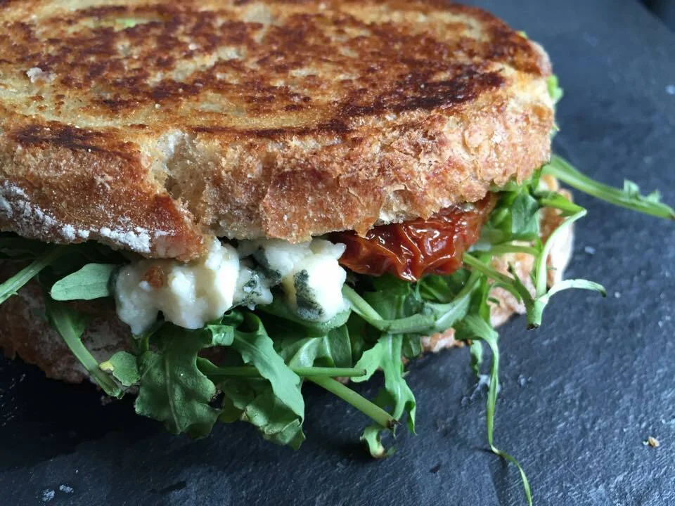 Sandwich with smashed avocado, sun-dried tomatoes, and Roquefort cheese