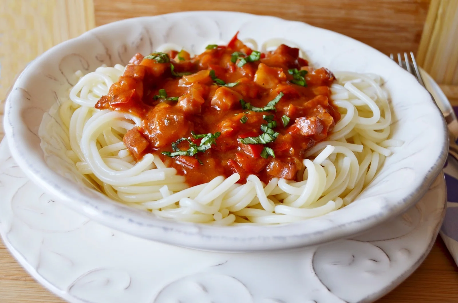 Spaghetti with ham, tomato sauce, and basil