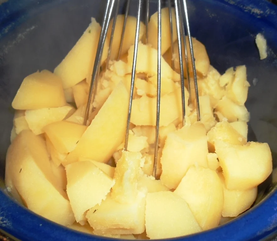 Mashed potato pudding with meat and sausages from the pot with lard